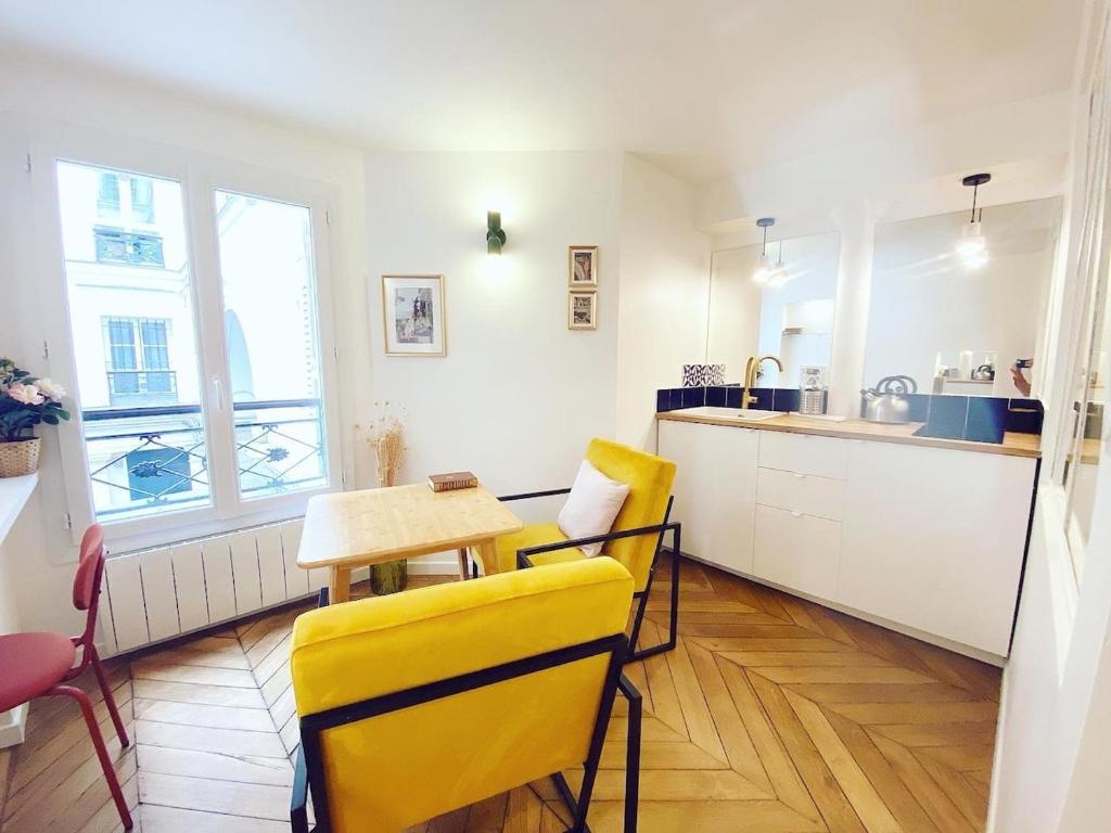 une cuisine avec des chaises jaunes, une table et un évier dans l'établissement Superbe appartement a Paris - FLAT-GUEST, à Paris