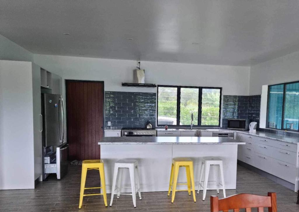 a kitchen with a white counter and yellow stools at Mama MIREKA Homestay in Arorangi