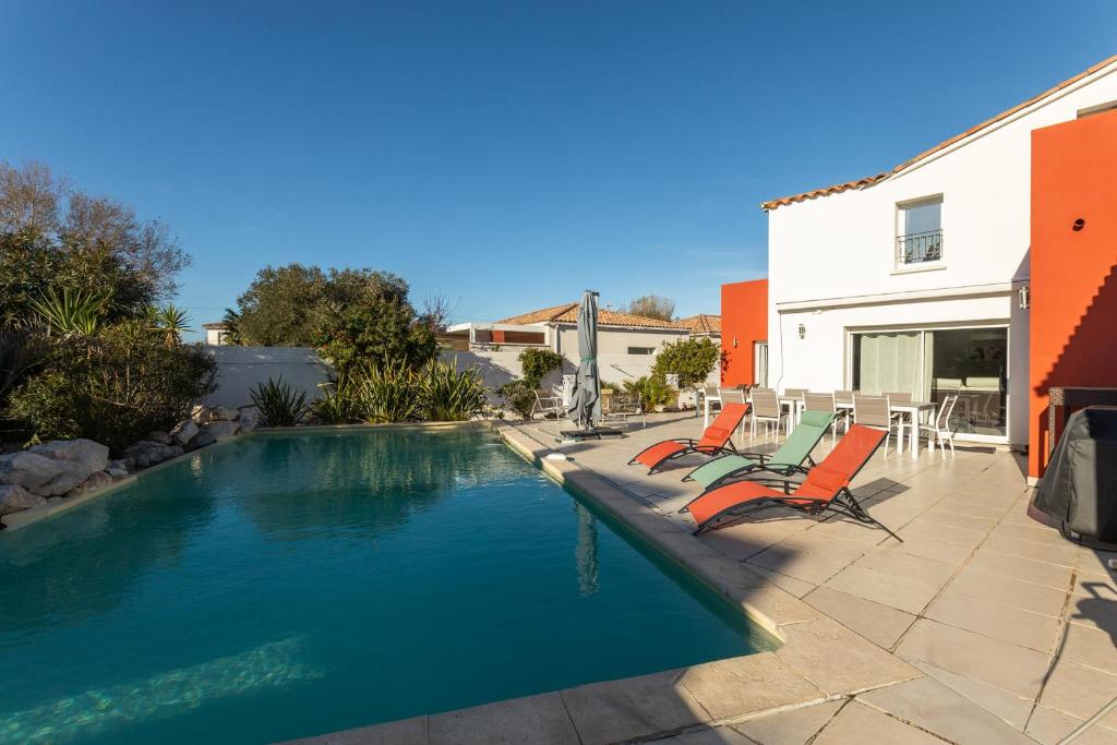 une piscine avec deux chaises et une table dans l'établissement Spacious 210 m villa in Cap d’Agde!, au Cap d'Agde