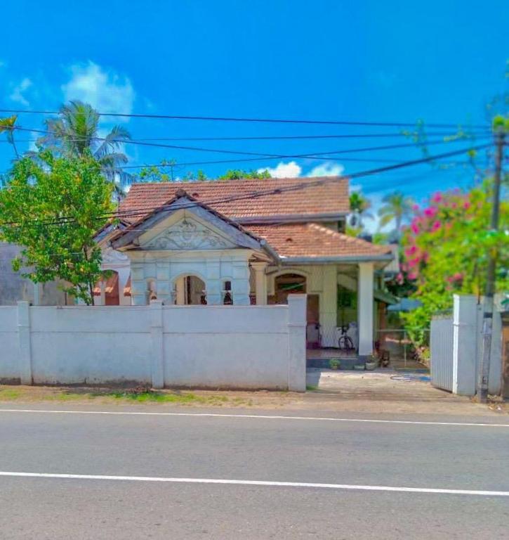 a house with a white fence in front of a street at Free House Bentota in Bentota