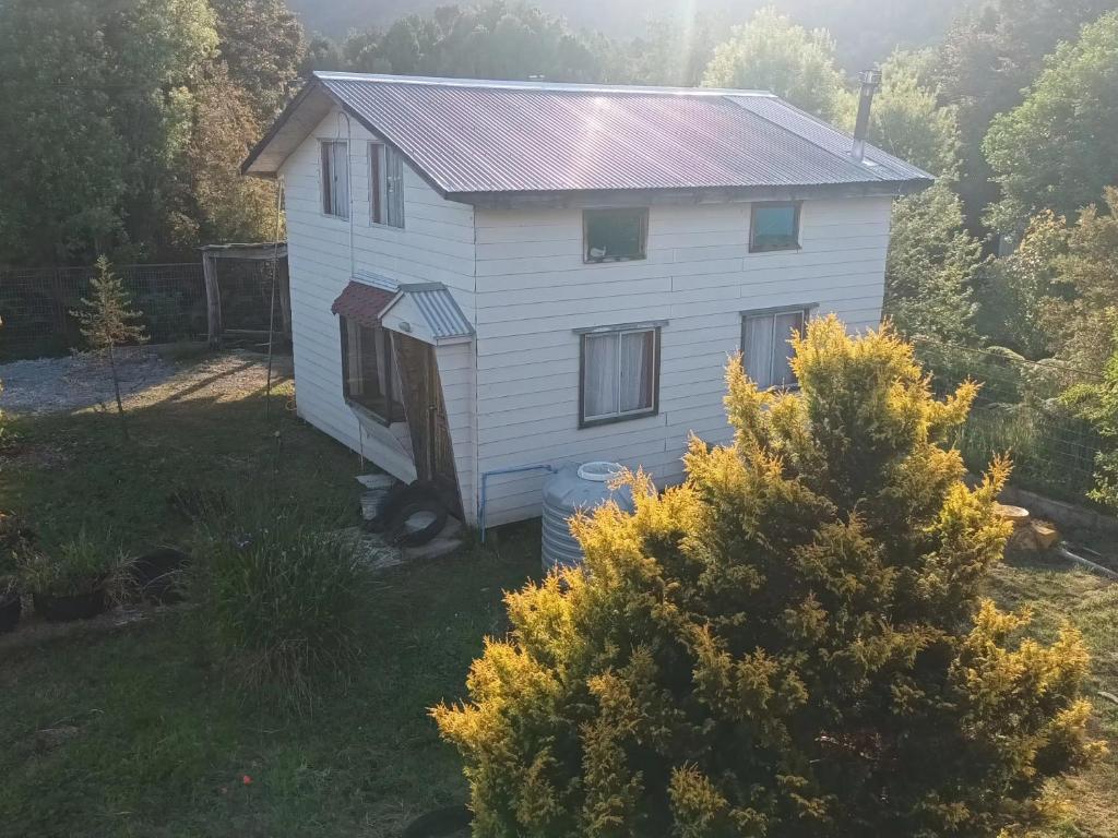a white house in the middle of a yard at Cabaña Hornopiren 1 in Hornopiren