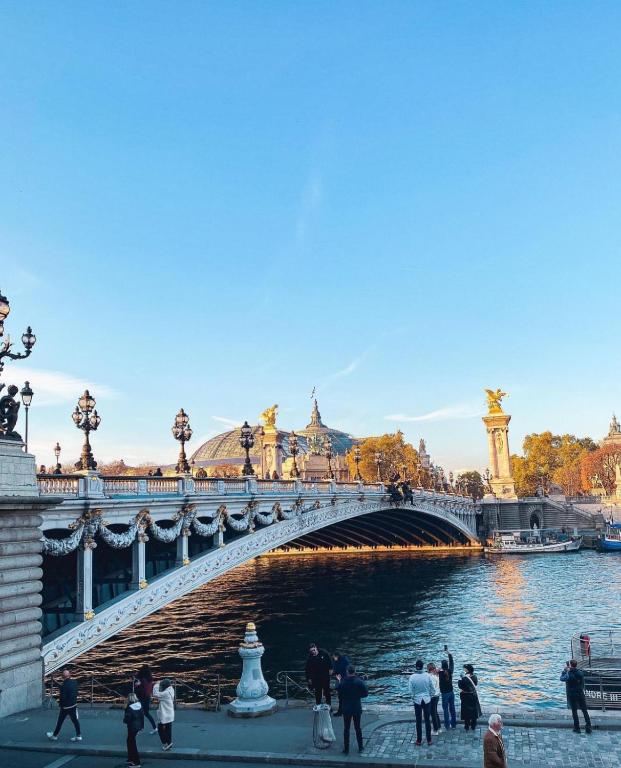 un pont sur une rivière avec des gens qui marchent sous celle-ci dans l'établissement Surcouf appartements, à Paris