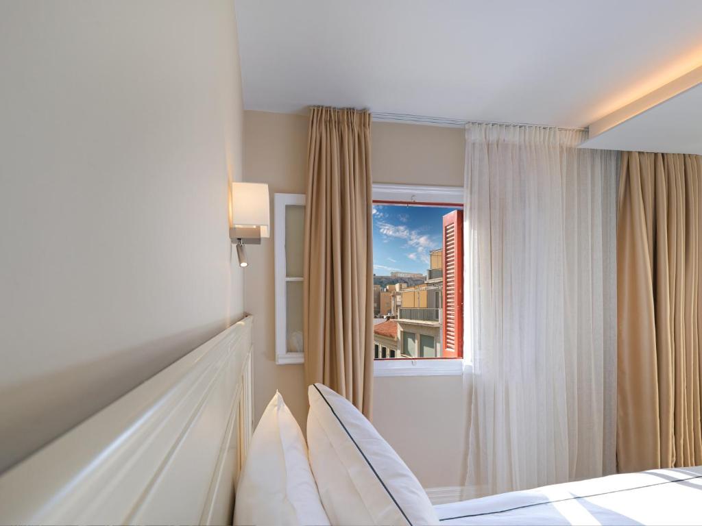 a bedroom with a bed and a window at Vrachos Athens Suites in Athens