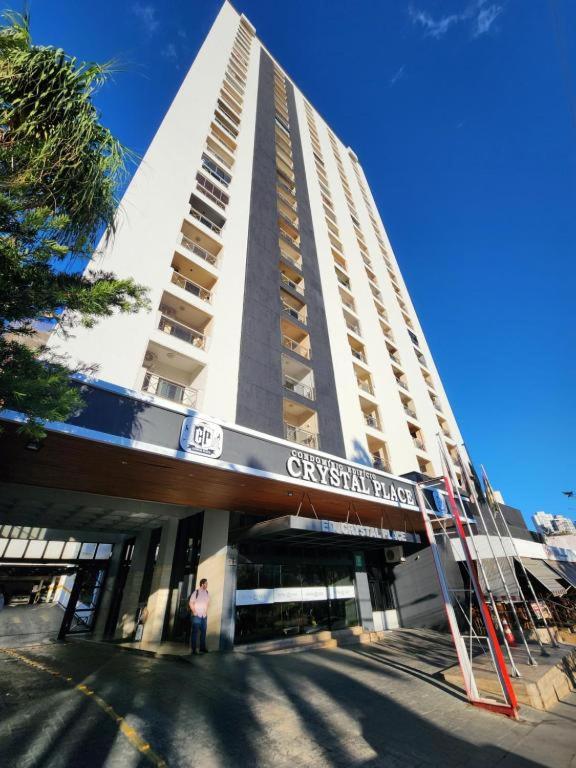 a man standing in front of a tall building at Flat Crystal Place in Goiânia