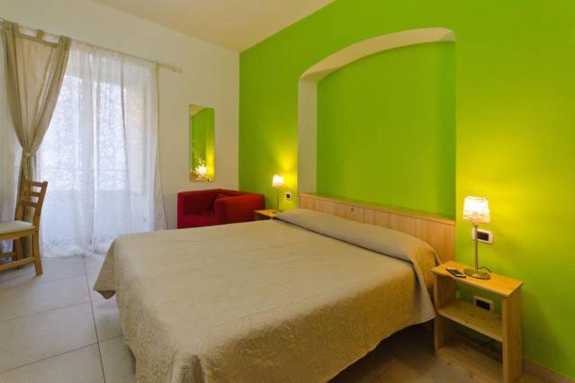 um quarto verde com uma cama e uma cadeira em B&B Alle Porte di San Giovanni em Roma