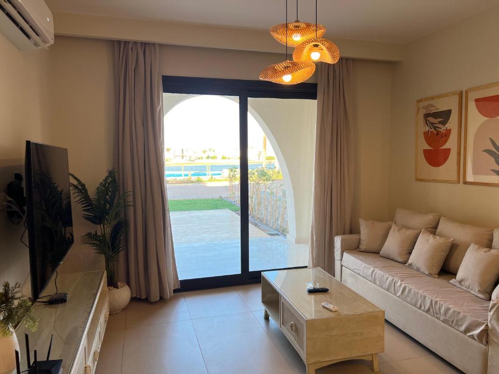 a living room with a couch and a large glass door at Stylish 1BR Ground With Free Pool & Lagoon Access In Gouna in Hurghada