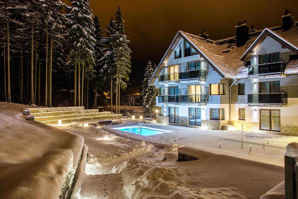 ein Haus mit Pool im Schnee in der Unterkunft Czarny Kamień Resort & SPA in Szklarska Poręba