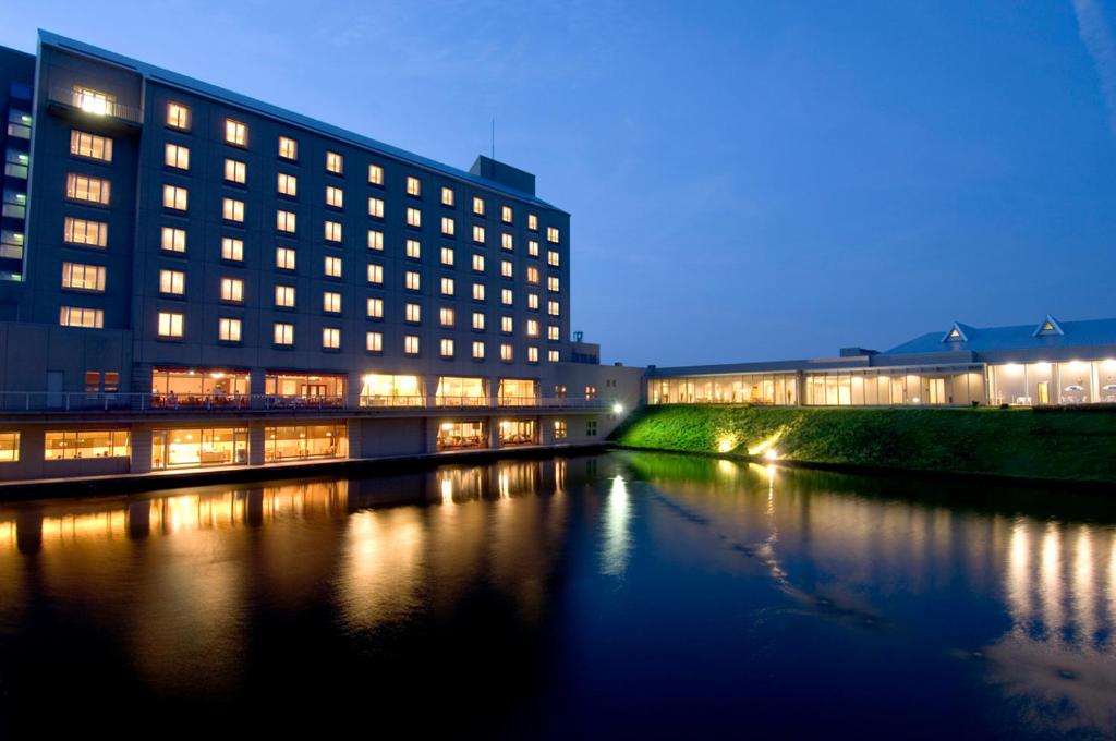 a building next to a river at night at Hotel Arrowle in Kaga