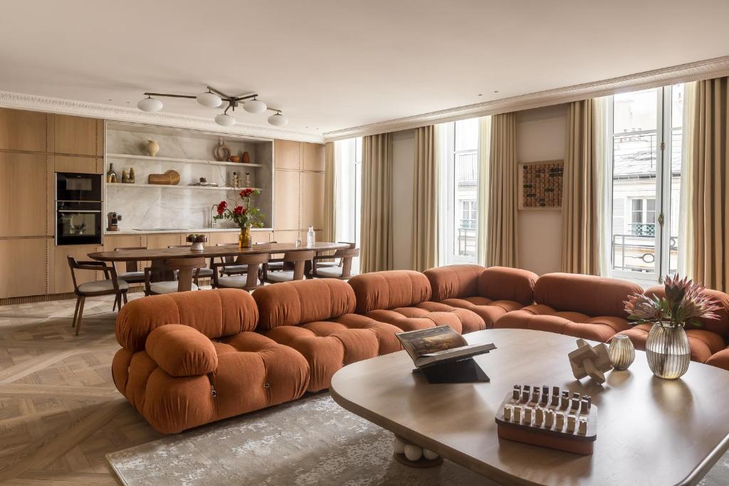 un salon avec un canapé marron et une table dans l'établissement HIGHSTAY - Luxury Serviced Apartments - Vendôme, à Paris