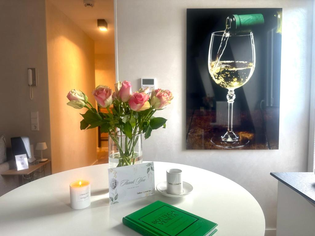 a table with a vase of flowers and a glass of wine at Modern Elegance in historical City Center in Trier