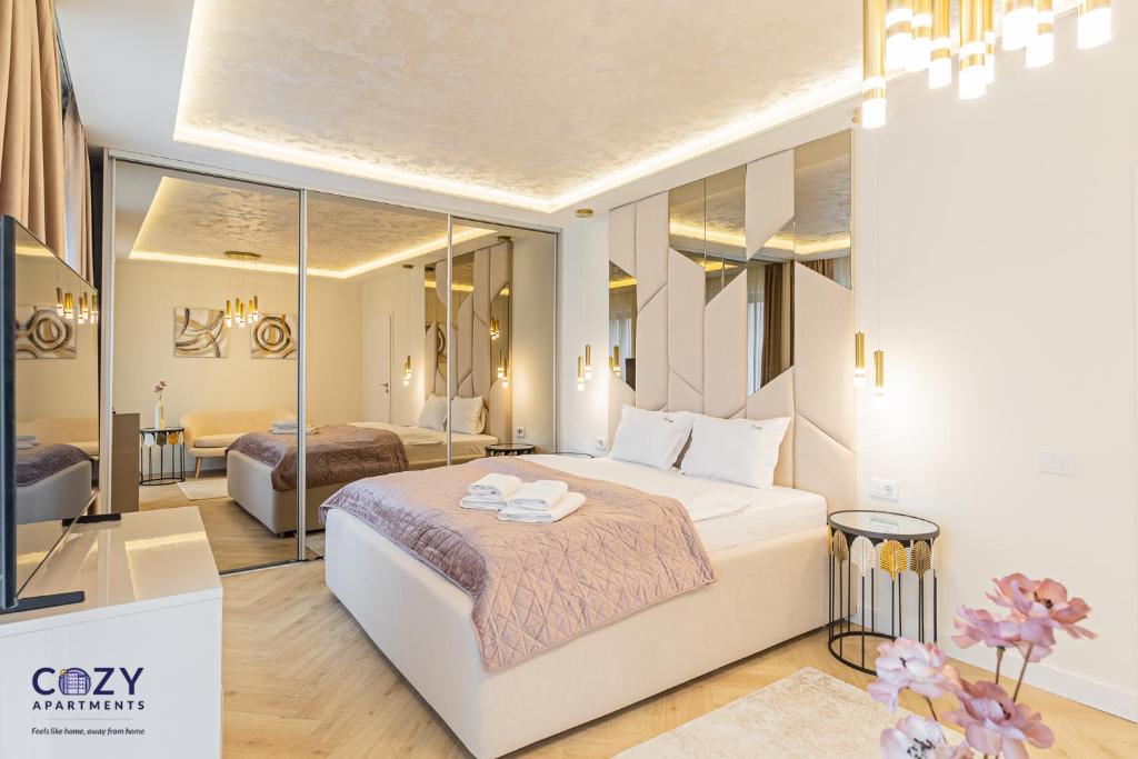 a bedroom with a large white bed and mirrors at COZY Aparthotel - Premium Suites and Studios in Braşov