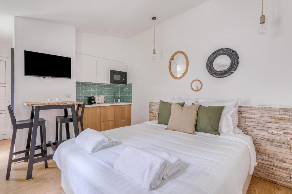 une chambre avec un grand lit blanc et une cuisine dans l'établissement Charming little house in th heart of Batignolles, à Paris