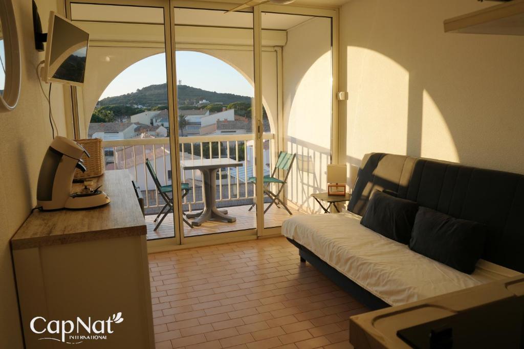 d'un salon avec un canapé et un balcon. dans l'établissement CapNat - Village Naturiste - Port Soleil - Le Capri Sun, au Cap d'Agde