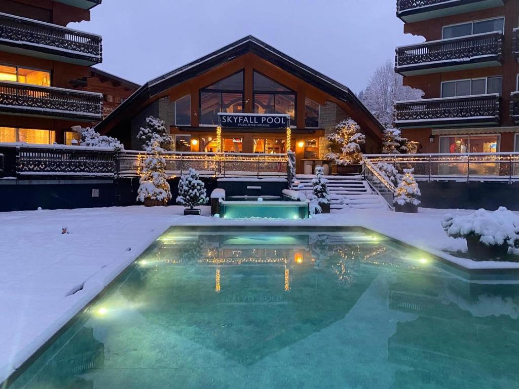 a swimming pool in the snow in front of a building at Hôtel Le Labrador 1971 in Les Gets