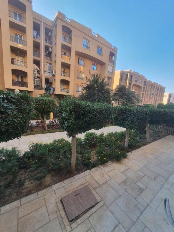 un grande condominio con una siepe in un cortile di TREE Serviced Apartment -2BHK Self check-in a Il Cairo