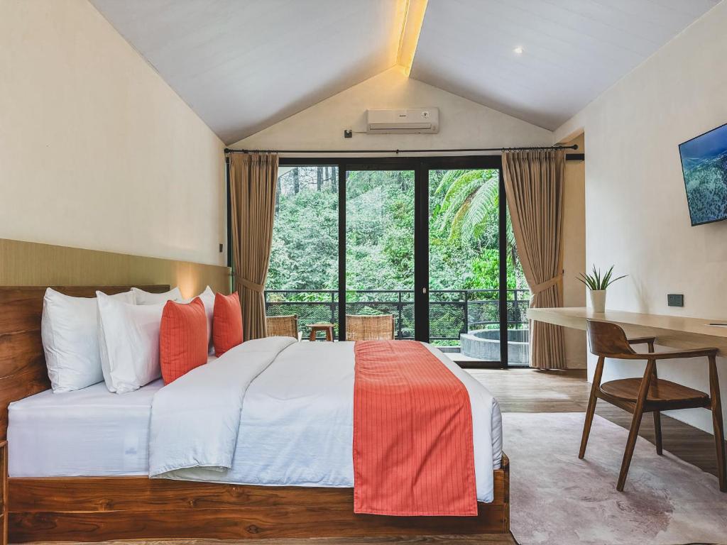 a bedroom with a large bed with a desk and a window at Arunika Villa in Ciloto