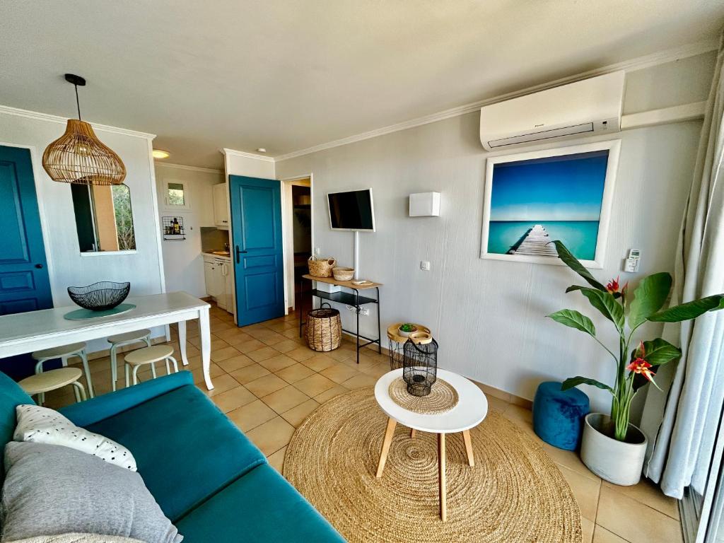 un salon avec un canapé bleu et une table dans l'établissement Les Restanques Roses 1178 vue mer, à Grimaud