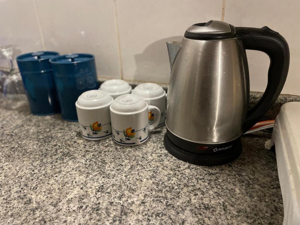 a coffee pot and three cups on a counter at Casa de campo larespampa in Urubamba