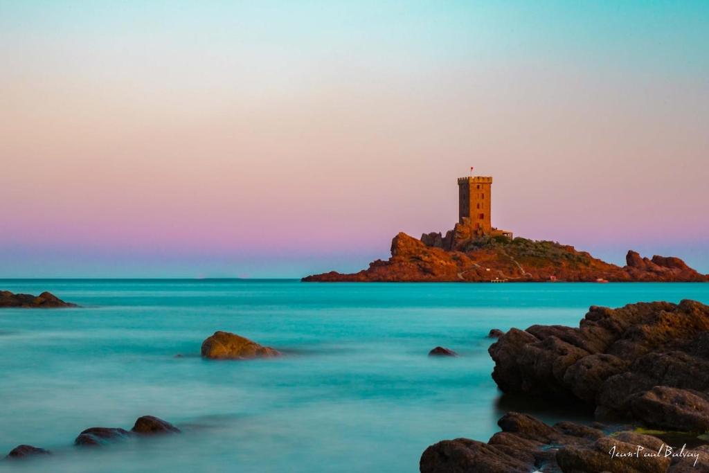 un phare sur une petite île dans l'océan dans l'établissement House with your feet in the water, between forest and beach - AGAY, à Agay