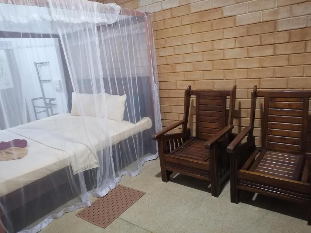ein Schlafzimmer mit zwei Stühlen und einem Bett und einem Fenster in der Unterkunft Green rooms in Weligama