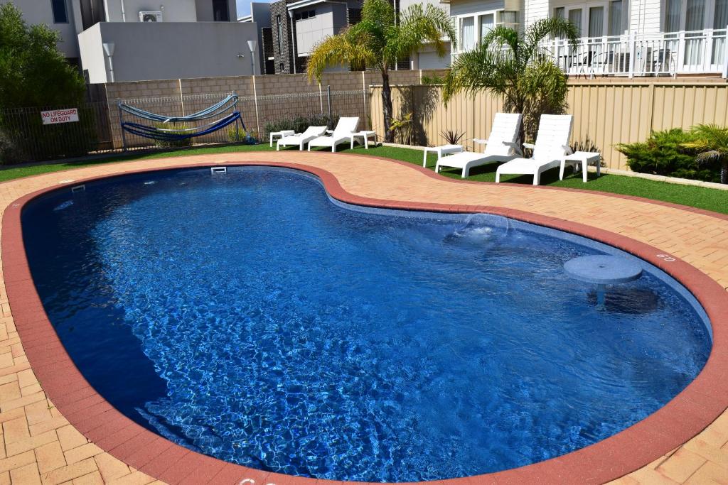 ein großer Pool mit Stühlen im Hof in der Unterkunft The Jetty Resort in Esperance