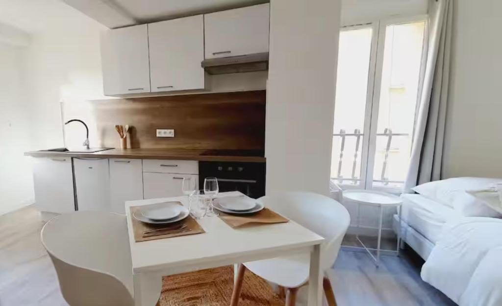 une cuisine blanche avec une table et des chaises blanches dans l'établissement 2 - Dagobert Cosy Studio Centre, à Perpignan