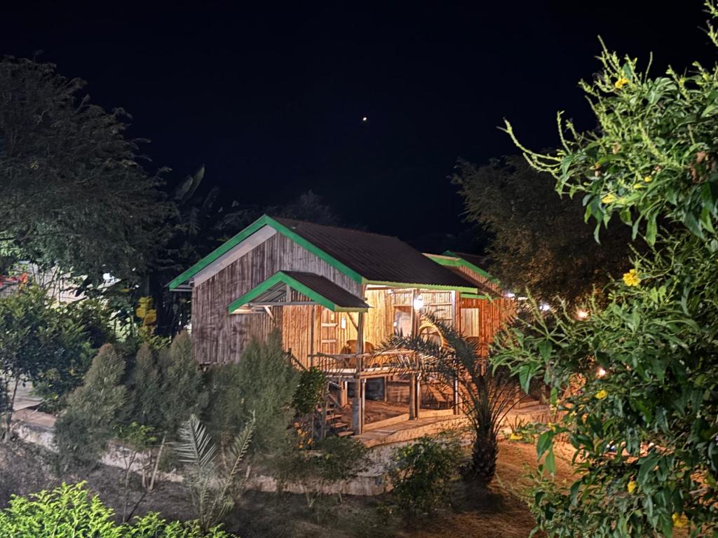 a wooden house with a green roof at night at บ้านสวนสาลี่ สวนผึ้ง ราชบุรี in Suan Phung