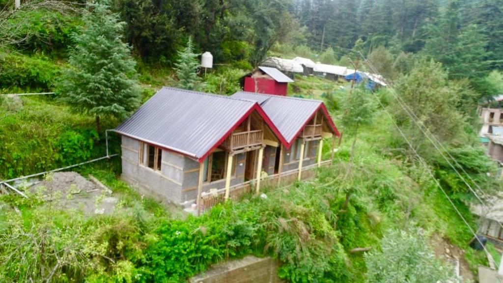 a small house on the side of a hill at woodland duplex cottage 2 Jibhi in Jibhi
