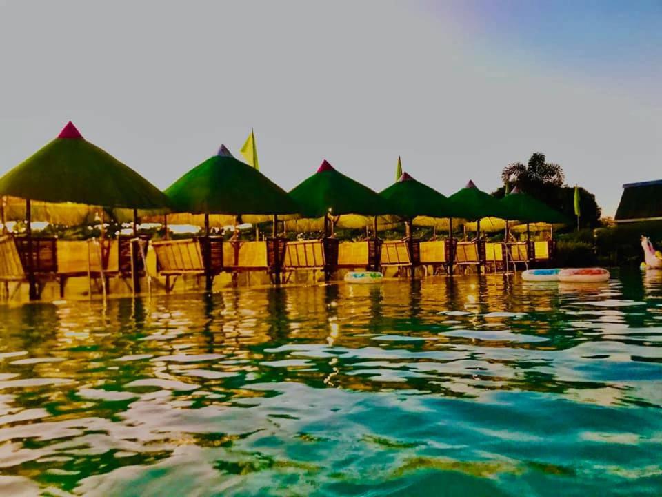 un groupe de chaises et de parasols dans l'eau dans l'établissement Mai Resort Hotel, à Laoac