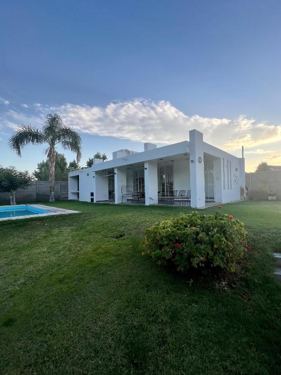 RivadaviaPuyuta beach的一座白色的建筑,有院子和棕榈树