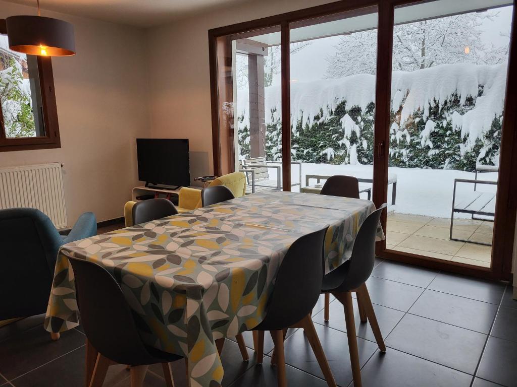 - une salle à manger avec une table, des chaises et de la neige à l'extérieur dans l'établissement Zorta - Ground floor apartment with private garden, à Samoëns