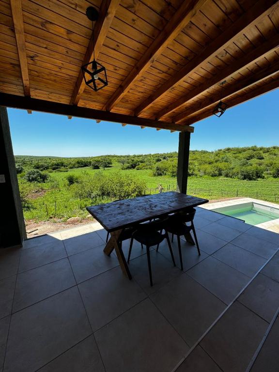 a picnic table under a wooden roof on a patio at Sierras de Córdoba Ascochinga vivienda Privada in Ascochinga