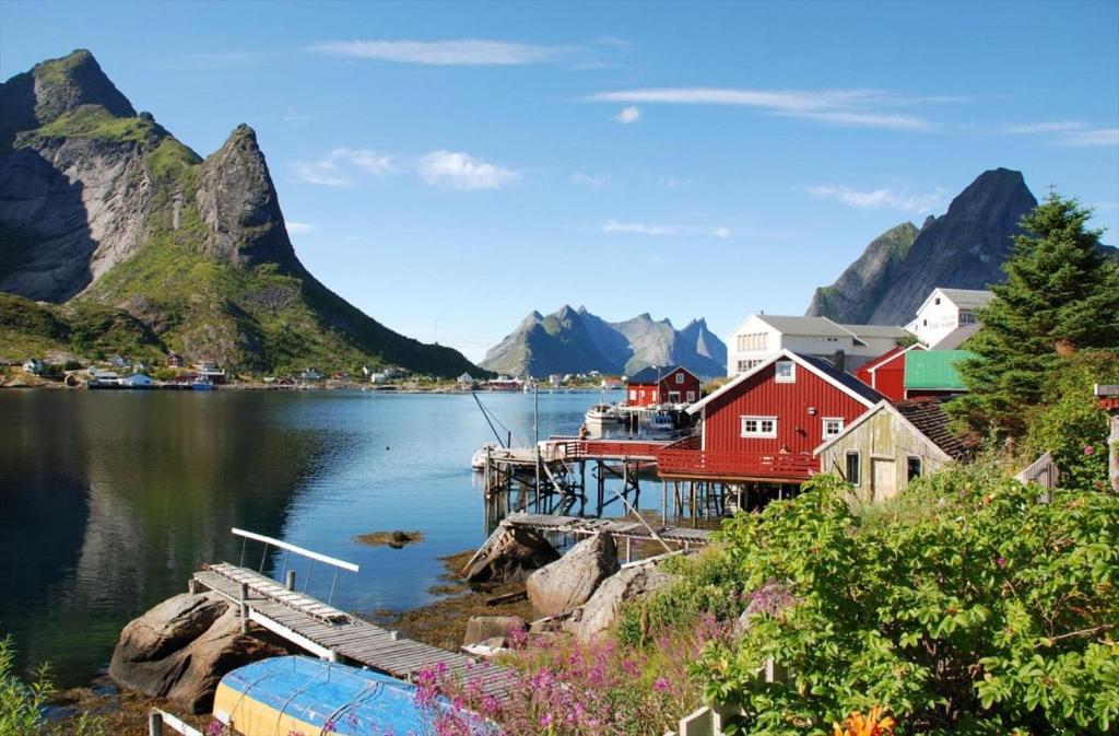 a village on a lake with mountains in the background at Reine Retro Villa - Cozy Villa With a Fantastic View in Reine