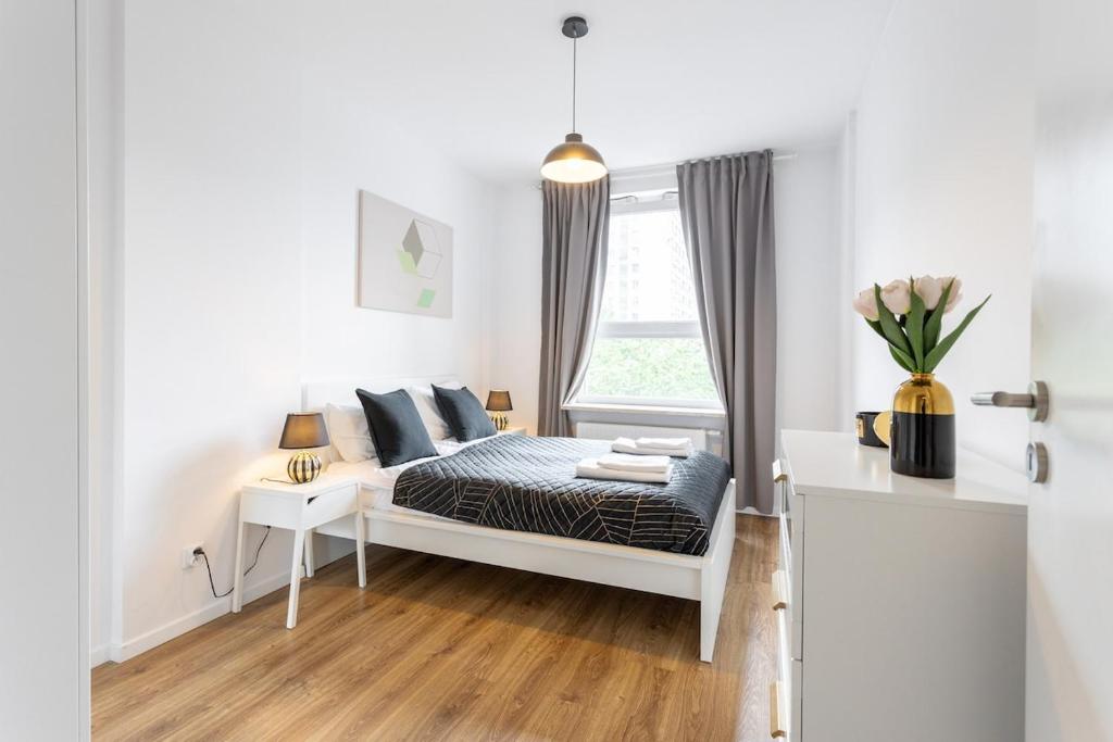 a white bedroom with a bed and a window at Urban Chic - Luxury 2-Bedroom Apartment in Warsaw City Center, Pereca Street in Warsaw