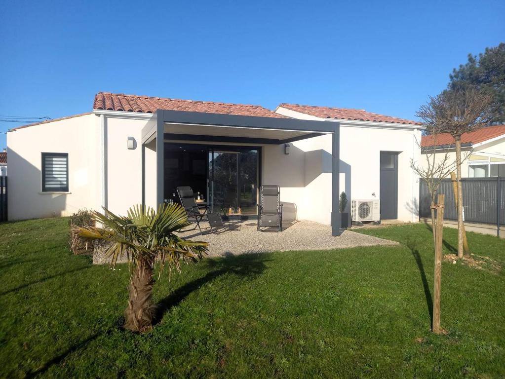 Maison blanche avec garage et palmier dans l'établissement Saint Palais sur Mer - BELLES PRESTATIONS avec un TERRAIN DE PETANQUE - WIFI, à Saint-Palais-sur-Mer