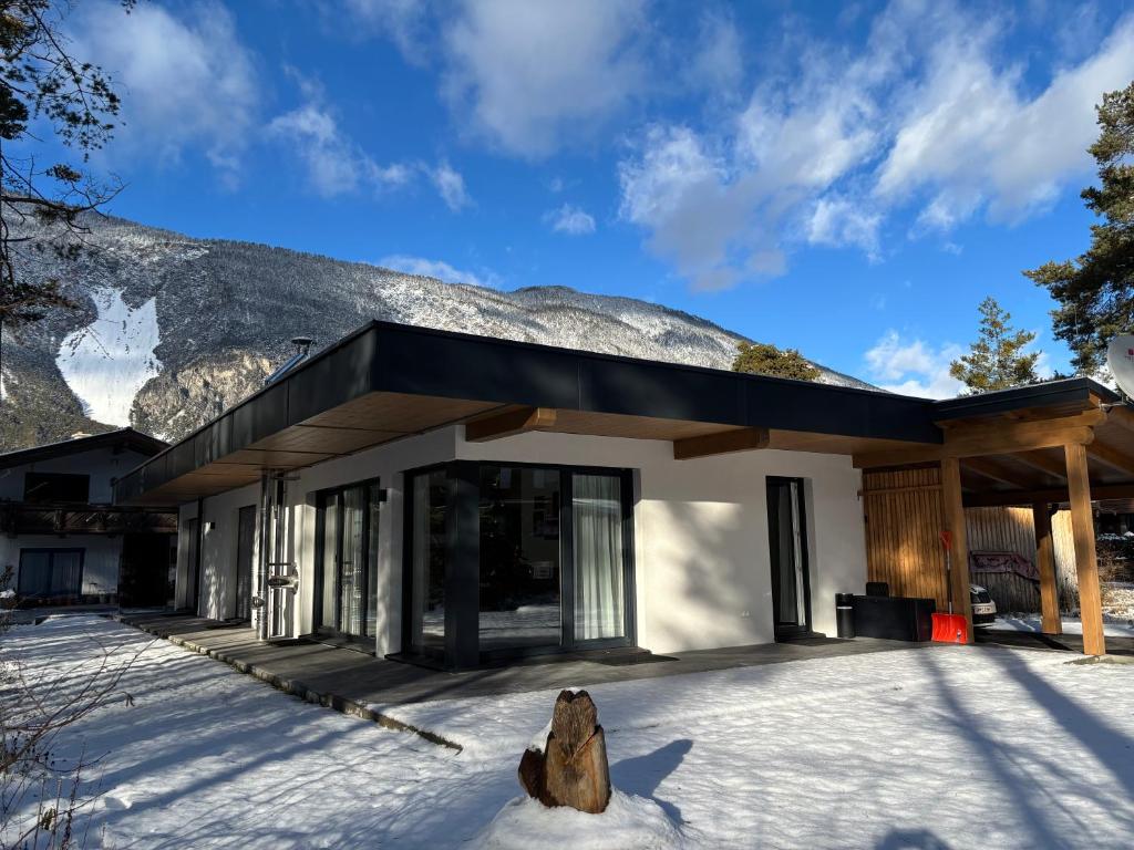 a building in the snow with a mountain in the background at Residenz Bergzauber in Ötztal-Bahnhof