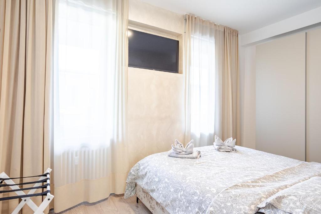 a bedroom with a bed with white sheets and windows at Teatro Romano Suites - Francesca in Trieste