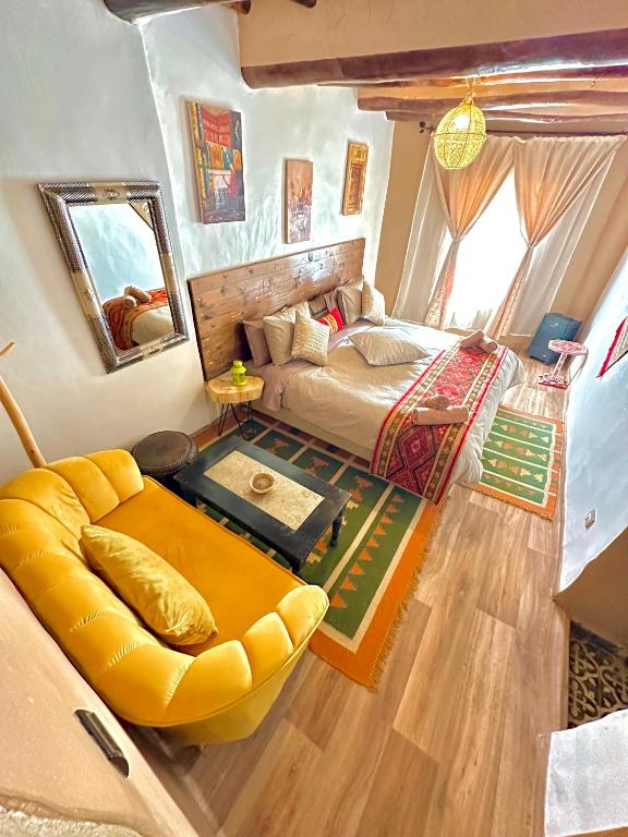 a bedroom with a bed and a large yellow couch at Kasbah El Hajja in Aït Benhaddou