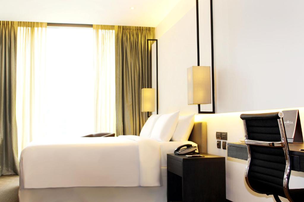 a hotel room with a white bed and a window at Amara Bangkok Hotel in Bangkok