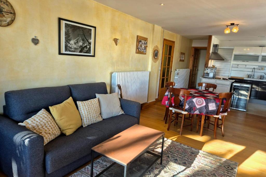 ein Wohnzimmer mit einem blauen Sofa und einem Tisch in der Unterkunft Appartement cosy au cœur de La Féclaz in La Feclaz
