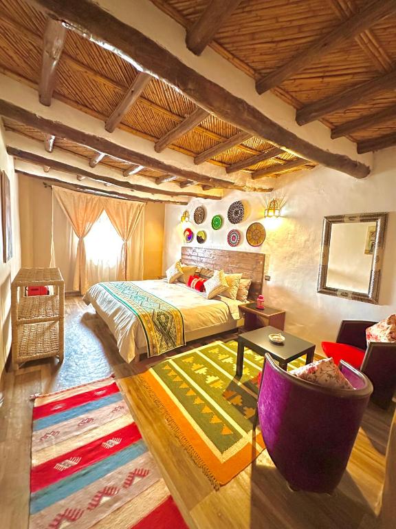 a bedroom with a king sized bed and a rug at Kasbah El Hajja in Aït Benhaddou