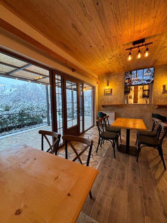 un ristorante con tavoli e sedie in legno e una grande finestra di Pubhouse & Rooms Pahulja a Kolašin