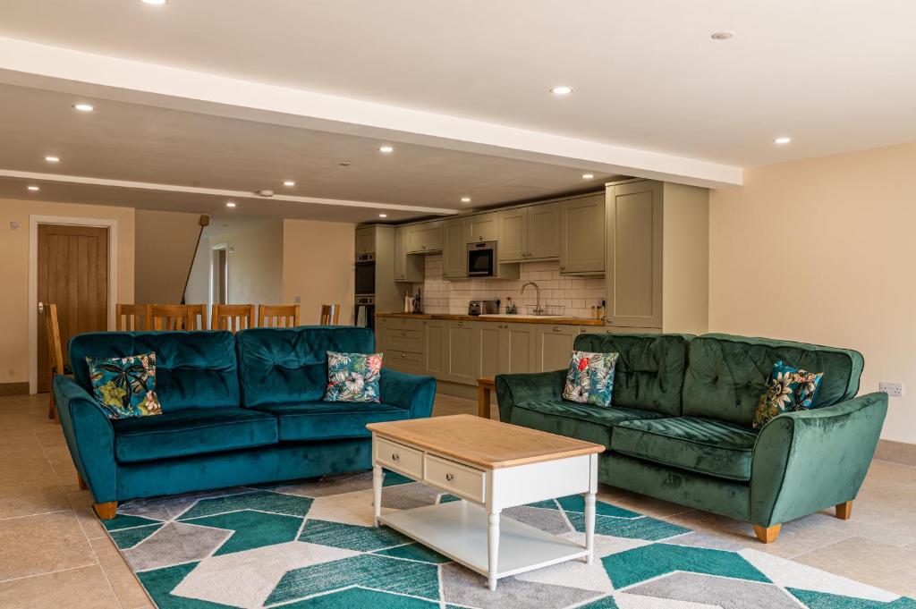 a living room with two blue couches and a table at Bears Court Barn 6 in Cheltenham