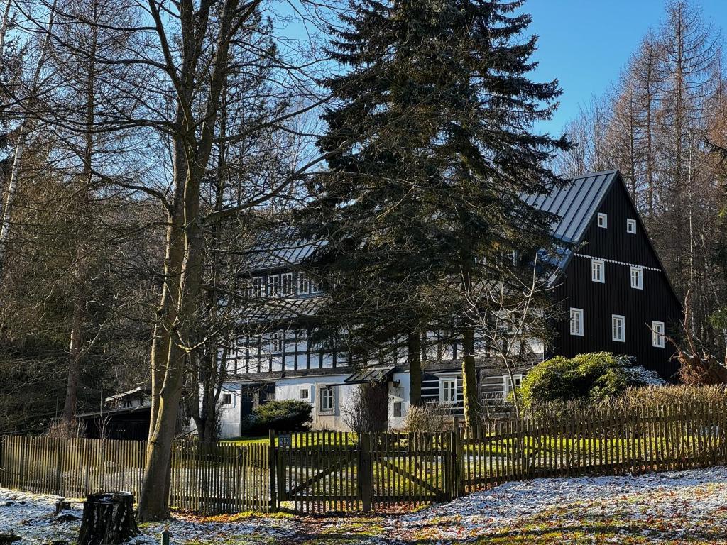 a black house with a fence and a tree at Chalupa Himmelreich in Ústí nad Labem