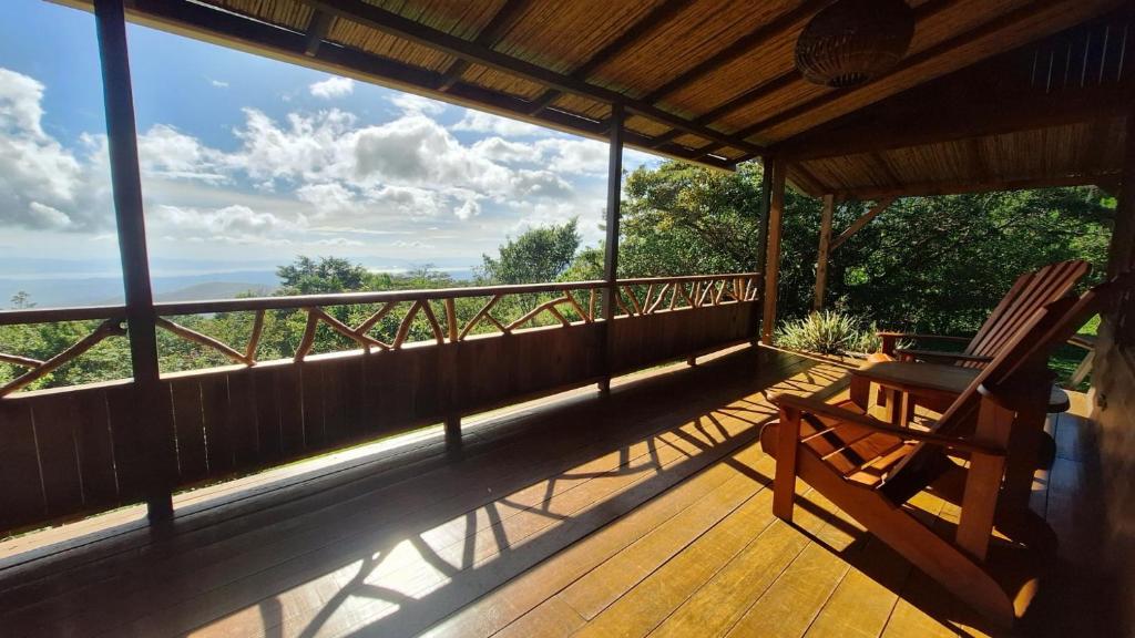 a porch with a rocking chair on a wooden deck at Casa Cabuya - Retro Style with Gulf View in Monteverde in Monteverde Costa Rica