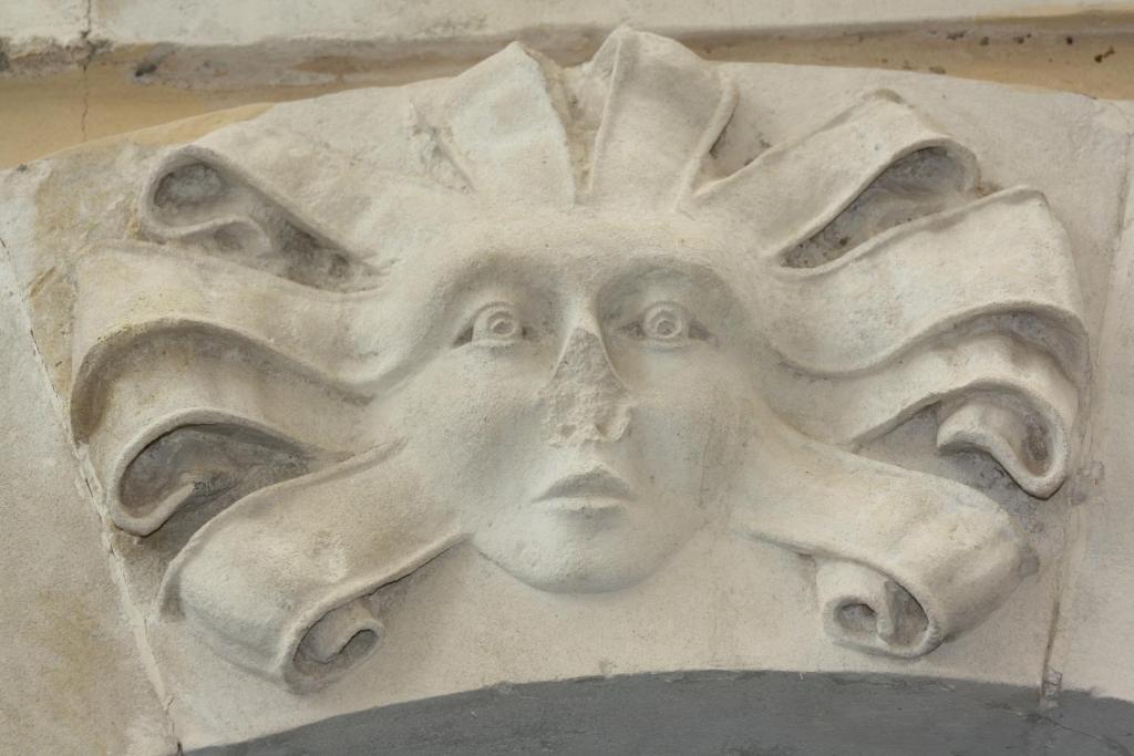 a stone sculpture of a face on a wall at La Chiave di Volta in Ragusa