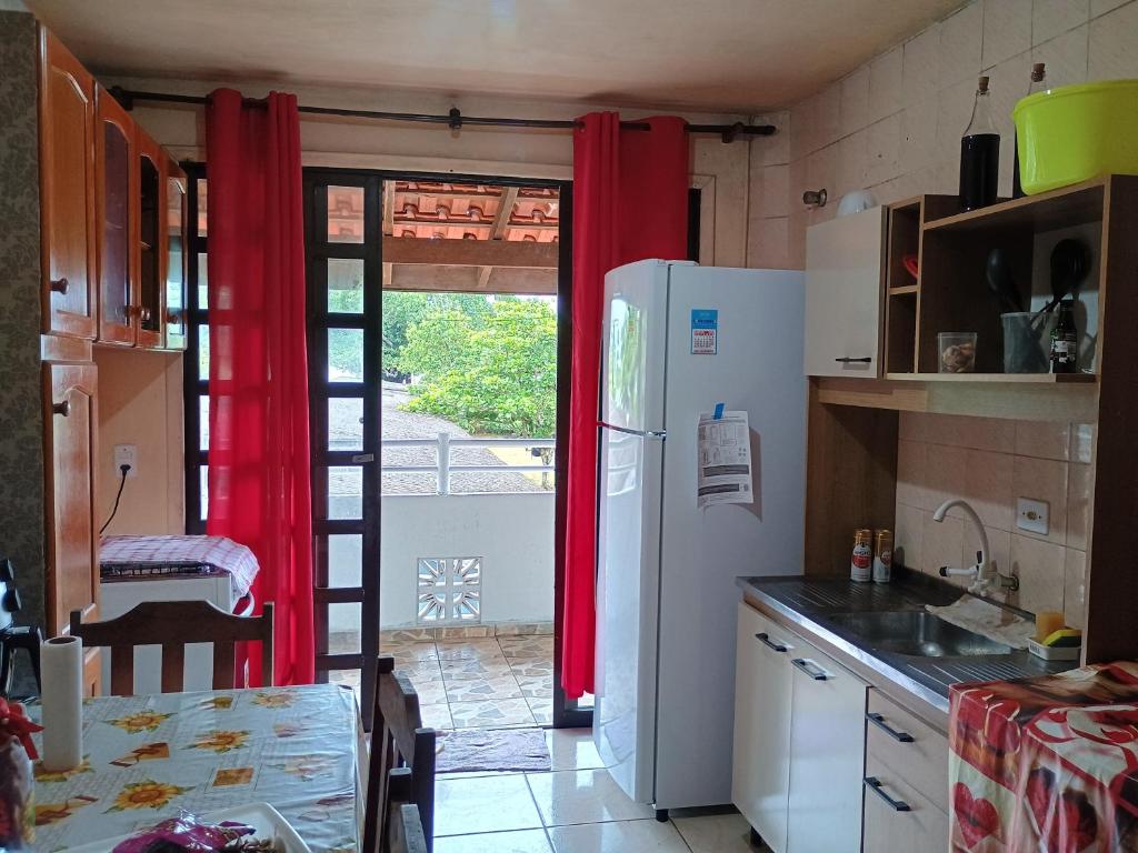 a kitchen with red curtains and a refrigerator and a table at Apto 20 QUADRA PRAIA CISSA in Itapoa