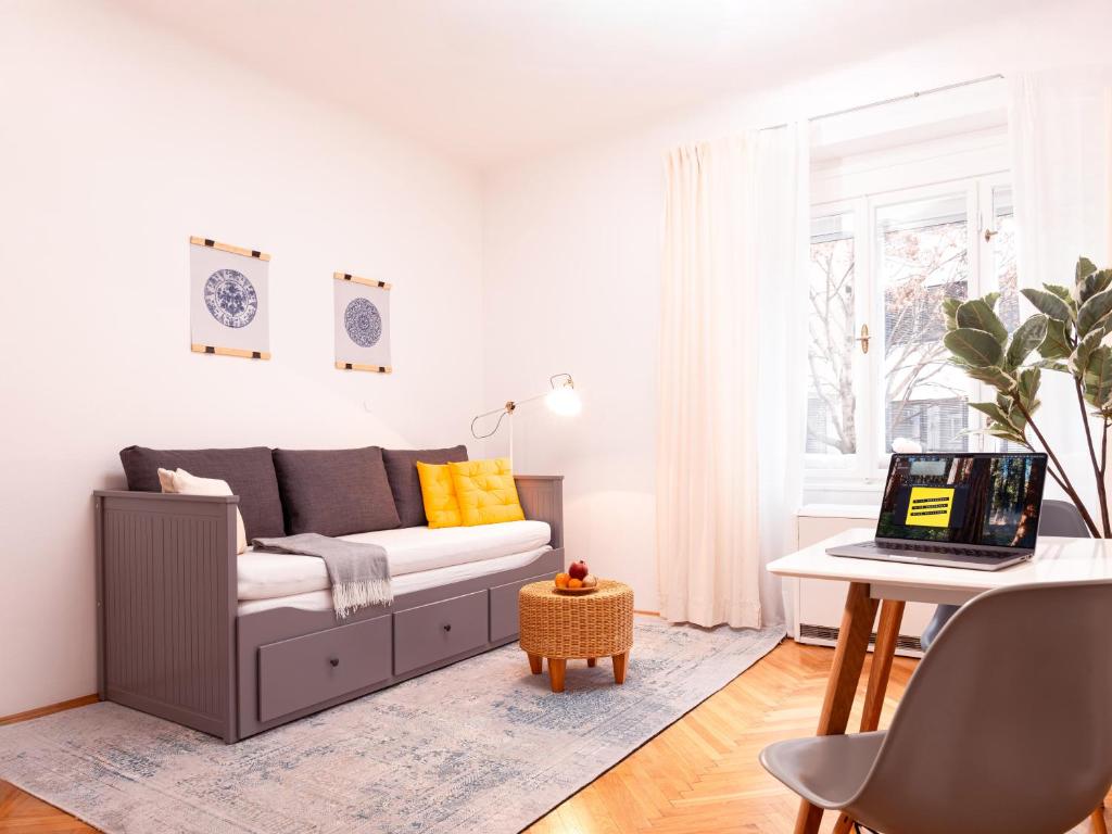 a living room with a couch and a table with a laptop at Nice Weekends Graz - Central & Cozy, Free Parking, Pets Welcome & Walk to Old Town - Mur - Kunsthaus in Graz