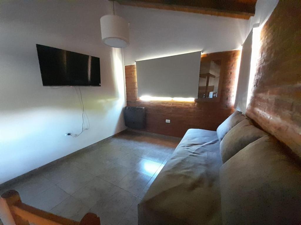 Una sala de estar con un sofá y un televisor de pantalla plana. en Acacias, en El Bolsón