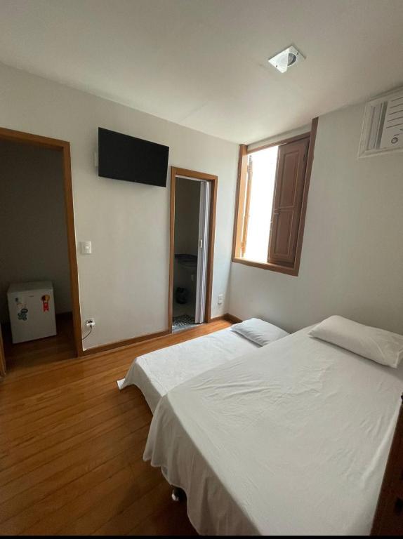 a room with two beds and a television on the wall at Suíte 302 - Pousada no Centro do Rio in Rio de Janeiro